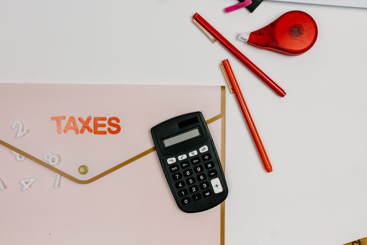 Flat lay image featuring a calculator, pens, and a folder labeled TAXES, perfect for finance-related themes.